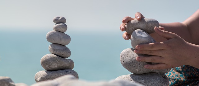 Balancing rocks and bundle of rocks in hands by the sea