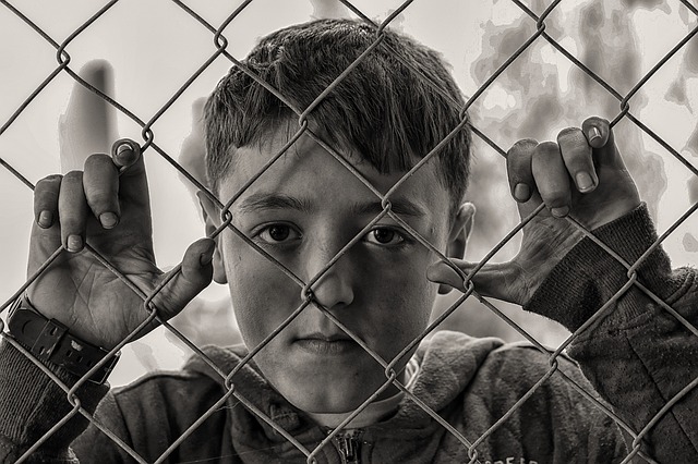 Black and white photo of a child behind a wire link fence