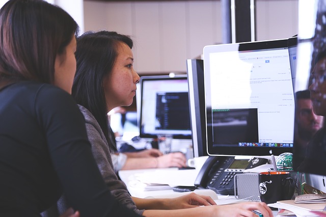 Two women in an office looking at one desktop monitor