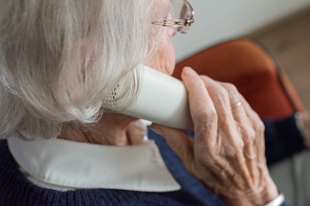 Old woman using telephone, face not visible