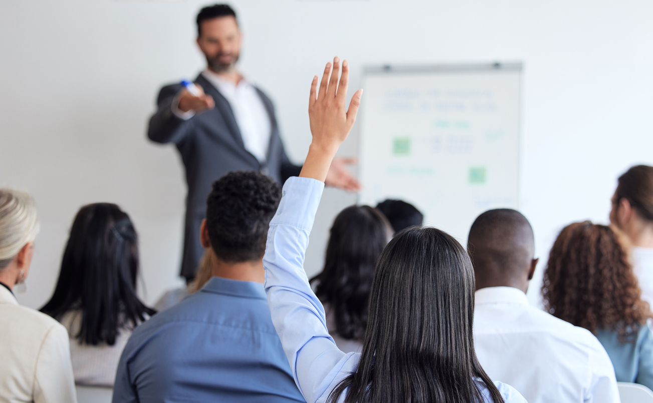 An apprentice raises their hand in a data academy seminar to ask a question.