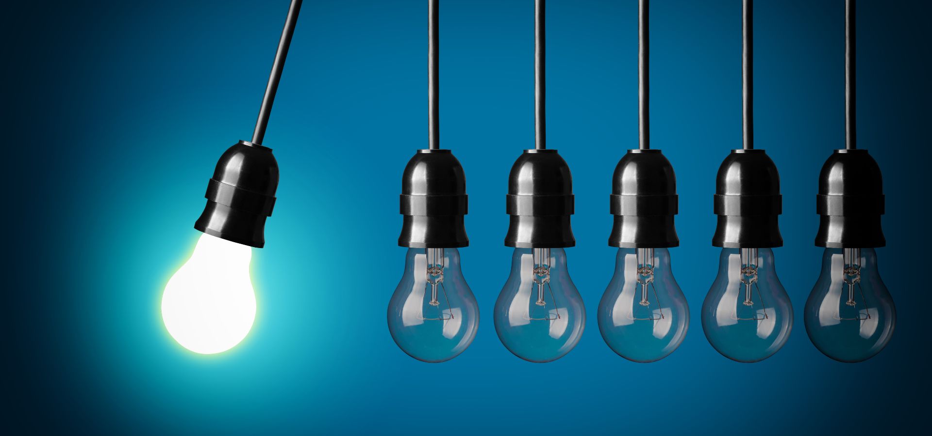 A chain of lightbulbs with one lit and swinging towards the others as if to create a chain reaction