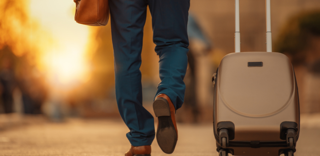Man pulling a suitcase through the street in an autumn light.